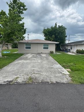 Fort Myers apartment for rent - A house with a grey roof and a concrete driveway in front.
