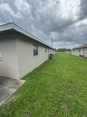 Fort Myers apartment for rent - A grassy area in front of a building with a cloudy sky above.