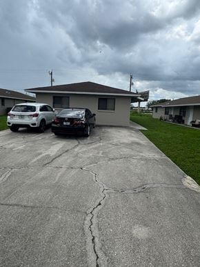 Fort Myers apartment for rent - A white car is parked in a driveway next to a black truck.