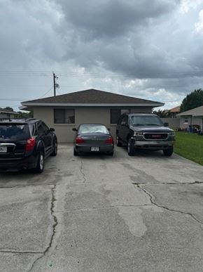 Fort Myers apartment for rent - Three cars are parked in a driveway in front of a house.