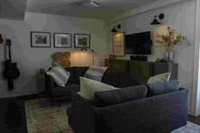 Scotsburn house for rent - A living room with a grey couch, a guitar, a vase with flowers, and a television.