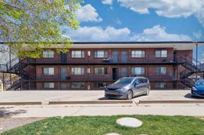 Denver apartment for rent - A silver car is parked in front of a red brick apartment building.