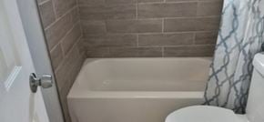 Atlanta house for rent - A white toilet sits next to a bathtub in a bathroom.