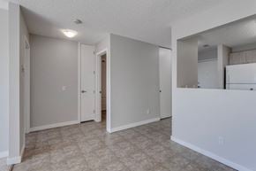 Edmonton apartment for rent - A spacious room with a door and a wall-mounted mirror.