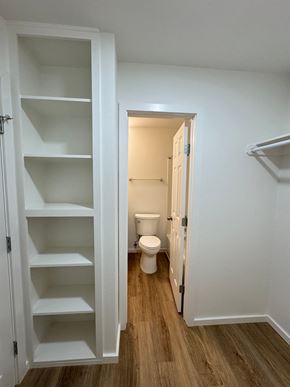 Austin apartment for rent - A white cabinet with shelves is open in a room with a toilet in the background.