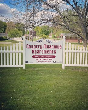 Delphos apartment for rent - A sign for Country Meadows Apartments is displayed on a white fence.