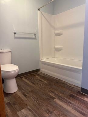 Wheeling apartment for rent - A white toilet sits next to a white bathtub in a bathroom.