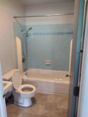 Byesville apartment for rent - A white toilet sits in a bathroom with a blue tiled shower.