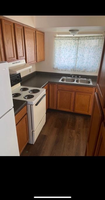 Logan apartment for rent - A kitchen with wooden cabinets and a white refrigerator.