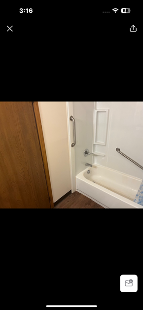 Logan apartment for rent - A white bathtub with a shower head and a wooden door.
