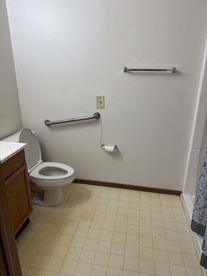 Minerva apartment for rent - A white toilet in a small bathroom with a grab bar.