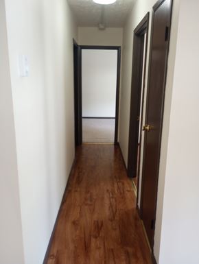 Summersville apartment for rent - A long hallway with a brown floor and white walls.