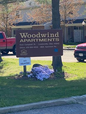 Loudonville apartment for rent - A sign for Woodwind Apartments is displayed in front of a tree.