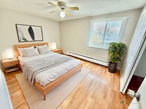 Denver apartment for rent - A bedroom with a bed, a ceiling fan, and a plant.