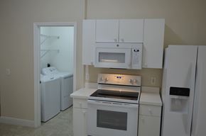 Cape Coral house for rent - A white kitchen with a microwave, oven, and refrigerator.