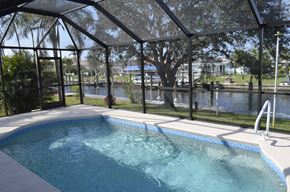 Cape Coral house for rent - A pool with a glass enclosure and a waterfall.