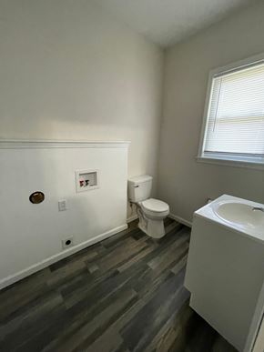 Lima house for rent - A bathroom with a toilet, sink, and wood flooring.