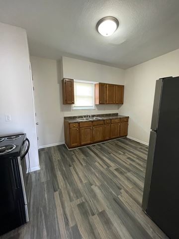 Lima house for rent - A kitchen with a black refrigerator and wooden cabinets.