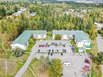 Quesnel apartment for rent - An aerial view of a parking lot with cars and a building with a green roof.