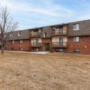 Omaha apartment for rent - Apartment building with brown brick exterior and a large grassy area in front.