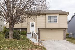 Omaha apartment for rent - A beige house with a white door and a small porch.
