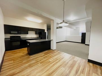 Council Bluffs apartment for rent - A kitchen with black cabinets and a wooden floor.