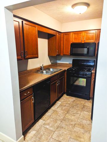 Omaha apartment for rent - A kitchen with black appliances and brown cabinets.
