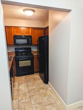 Omaha apartment for rent - A kitchen with black appliances and wooden cabinets.