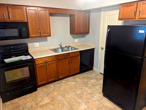 Omaha apartment for rent - A kitchen with black appliances and wooden cabinets.