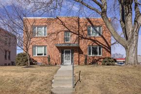 Omaha apartment for rent - A red brick house with a grey door and steps leading up to it.