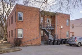 Omaha apartment for rent - A red brick building with a car parked in front.