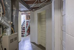 Omaha apartment for rent - A long hallway with a door on the right and a furnace on the left.