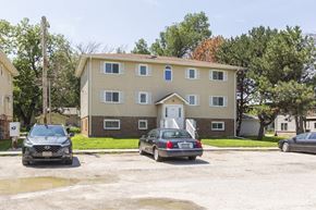 Ashland apartment for rent - A two-story building with a beige exterior and a brown roof is surrounded by parked cars.