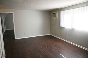 Omaha apartment for rent - A room with wooden floors and a window with curtains.