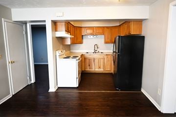 Omaha apartment for rent - A kitchen with wooden cabinets and a black refrigerator.