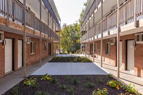 Omaha apartment for rent - A long, narrow courtyard between two rows of red brick buildings with white doors.