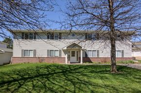 Gretna apartment for rent - A house with a grey roof and a white door is surrounded by a green lawn.