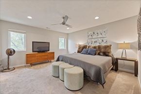 Omaha townhouse for rent - A bedroom with a bed, a dresser, a television, and a ceiling fan.