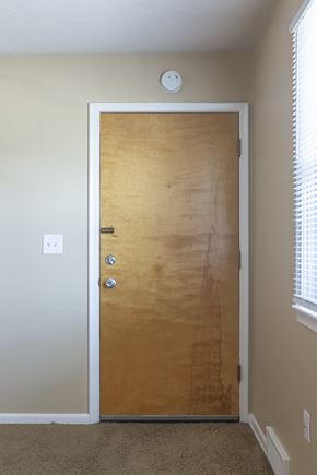 Omaha apartment for rent - A brown door with a silver handle and a round white thing on the ceiling.
