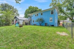 Bristol apartment for rent - A blue house with a white door and windows is surrounded by a green lawn.
