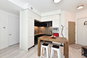 Toronto apartment for rent - A modern kitchen with a wooden table and bar stools.