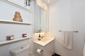 Toronto apartment for rent - A white bathroom with a toilet, sink, and towel rack.