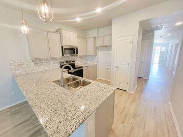 Copperas Cove house for rent - A kitchen with a granite countertop and white cabinets.