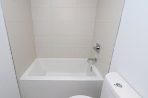 Toronto apartment for rent - A white bathroom with a tub, toilet and sink.