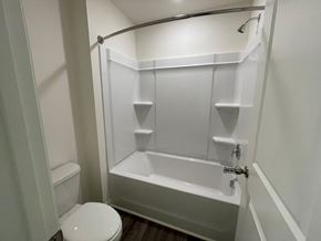 Wilson apartment for rent - A white bathroom with a toilet, tub, and shower.