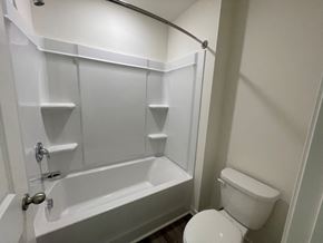 Wilson apartment for rent - A white bathroom with a toilet and a bathtub.