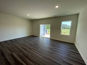 Wilson apartment for rent - A room with wooden flooring and a view of a grassy field through a window.