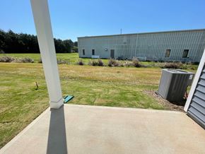 Wilson apartment for rent - A large metal building with a grey roof is surrounded by a grassy field.