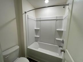 Wilson apartment for rent - A white bathroom with a toilet, tub, and towel rack.