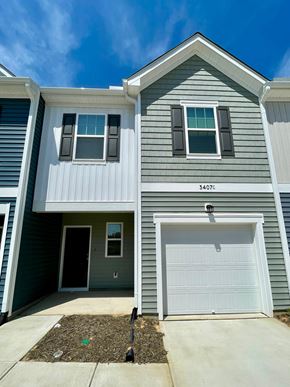 Wilson apartment for rent - A two-story house with a garage door and a window on the front.